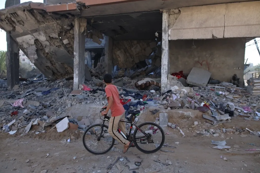 a young boy on bike in front of rubble