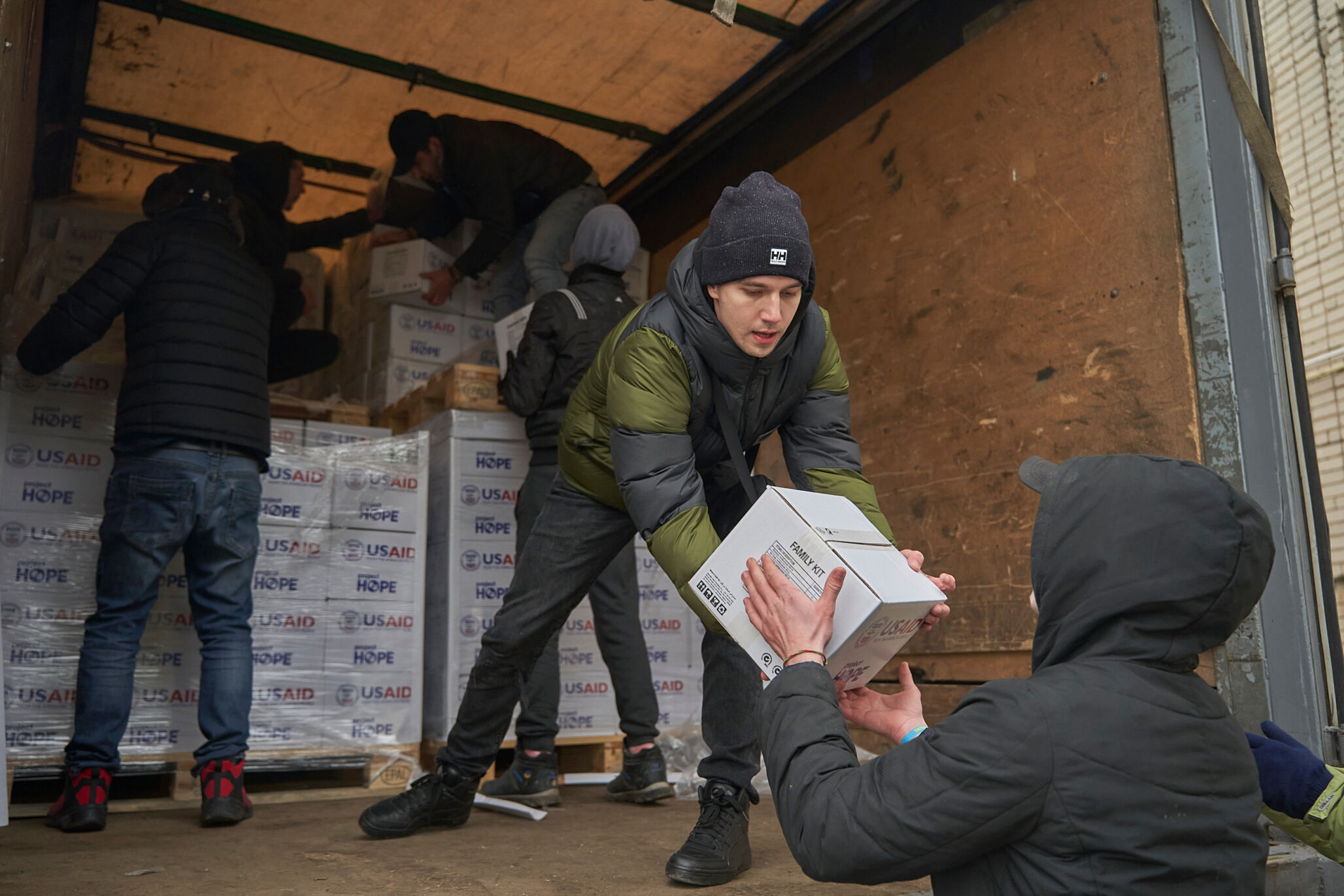 man passes box of medical equipment to another man from a truck