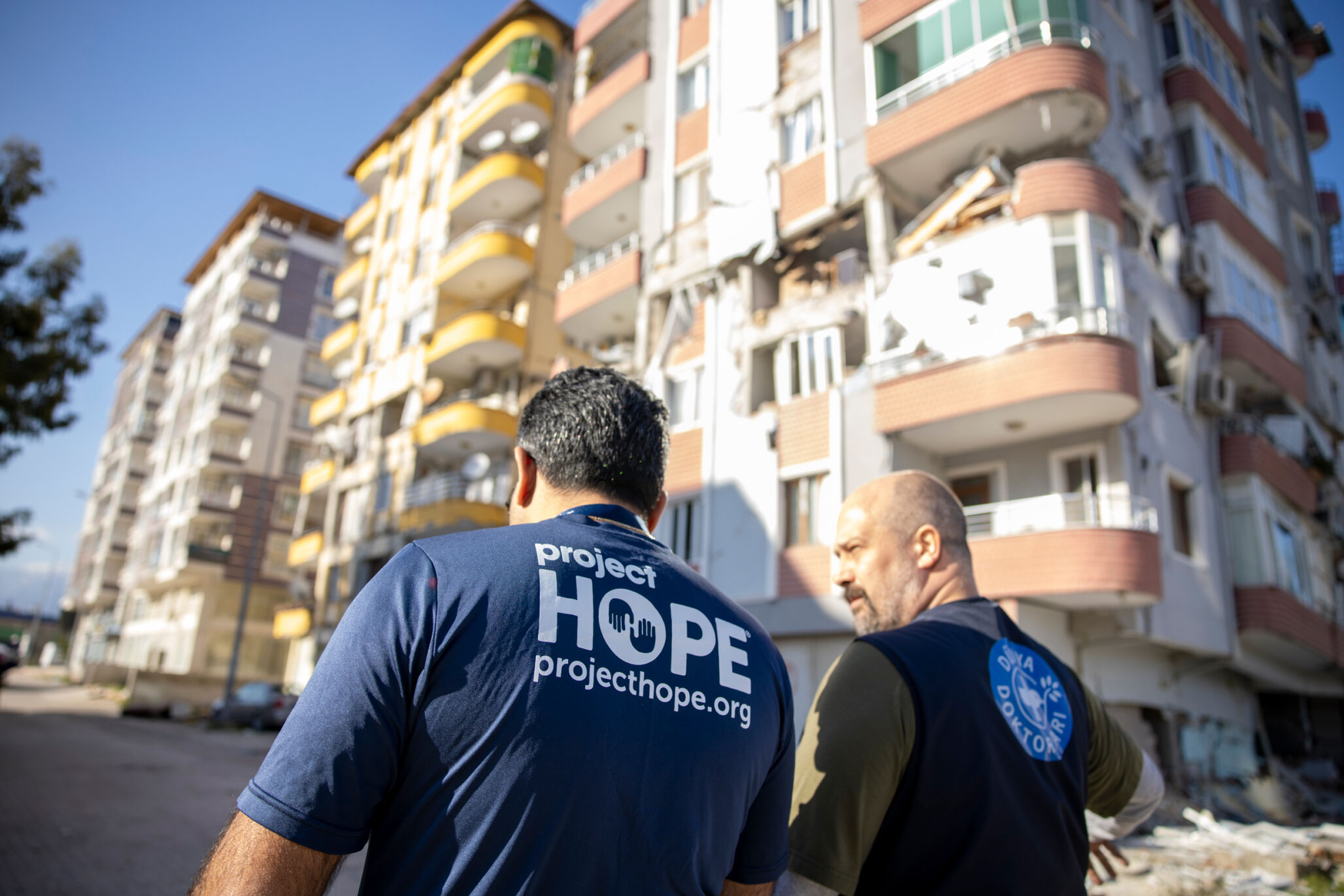 Two aid workers walking through destruction in Turkiye after the earthquake