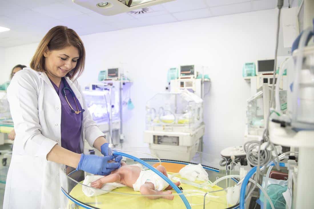 Female medical worker works with newborn in hospital