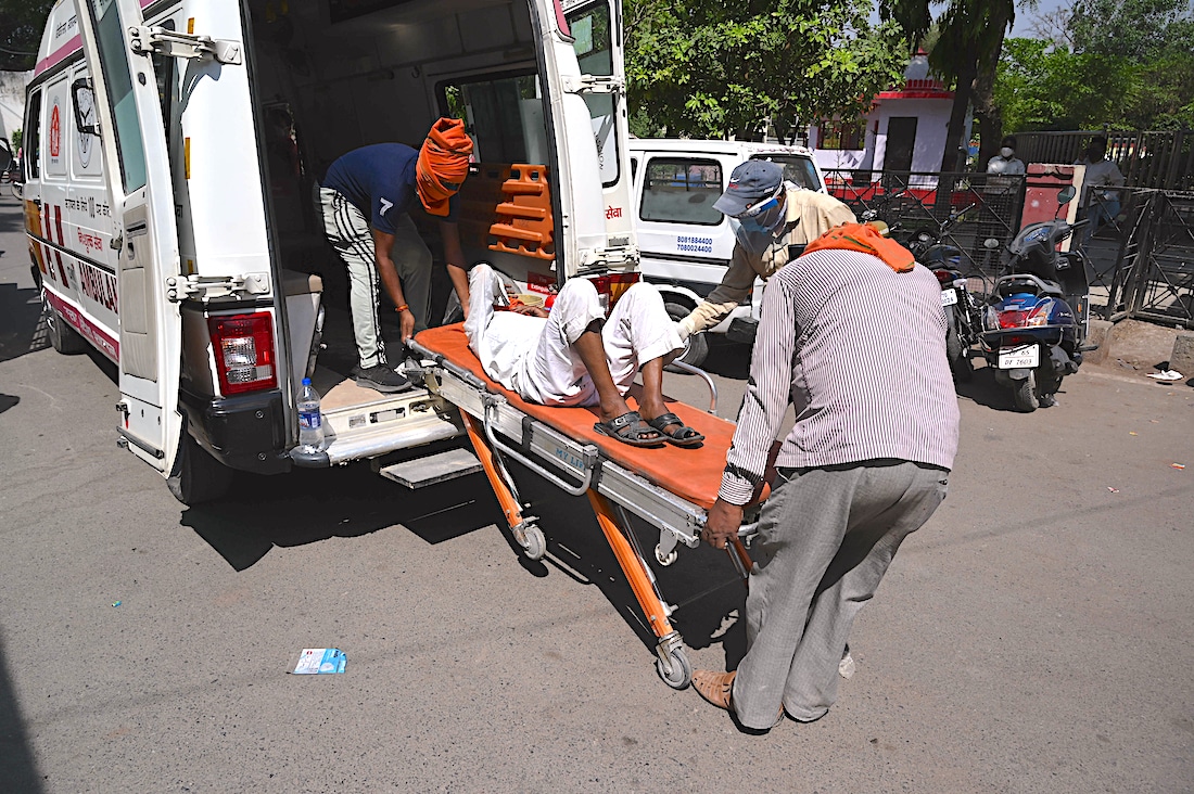 man being loaded into ambulance in India