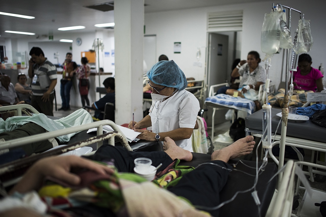 medical staff takes vitals of patient in overpacked hospital