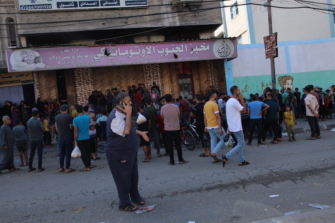 group of people standing outside of bakery for food