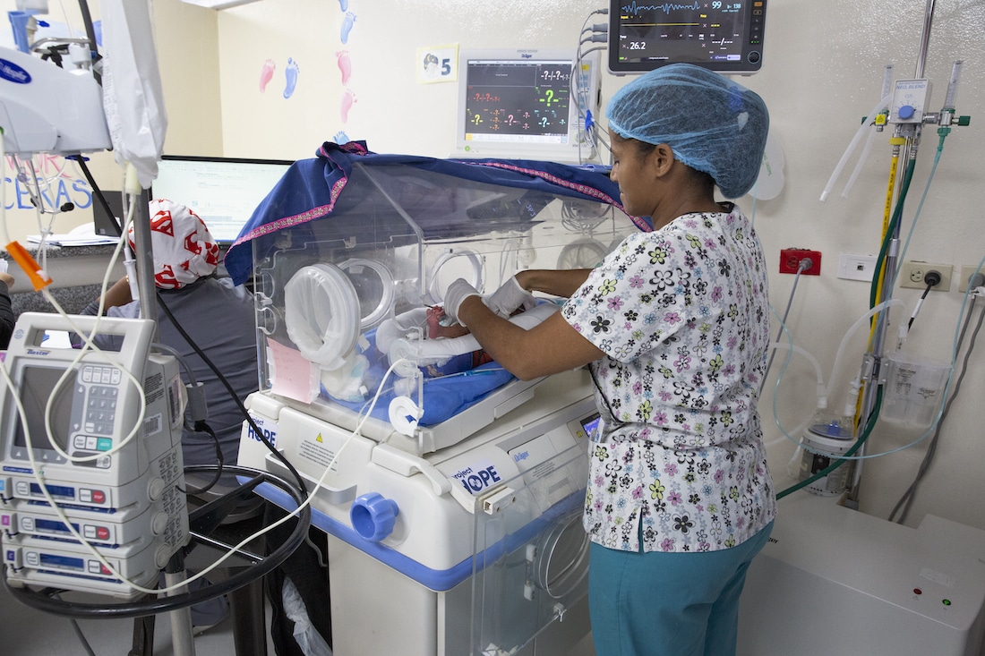 a nurse checking in on a newborn baby in a NICU