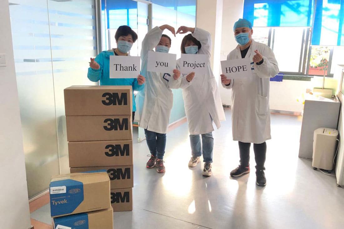 Doctors holding a thank you sign in front of donated supplies.