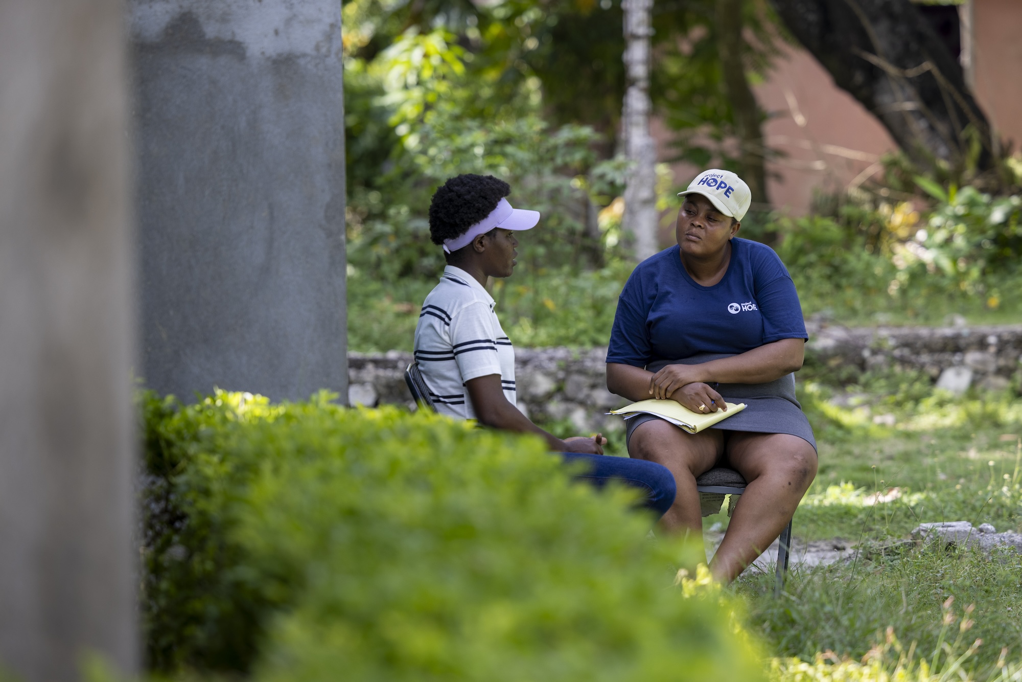 woman in Project HOPE gear speaks with patient in Haiti