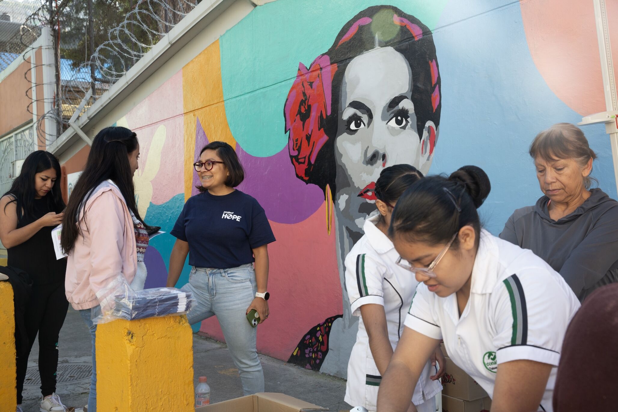 group of women and young girls in discussion in front of mural in Mexico