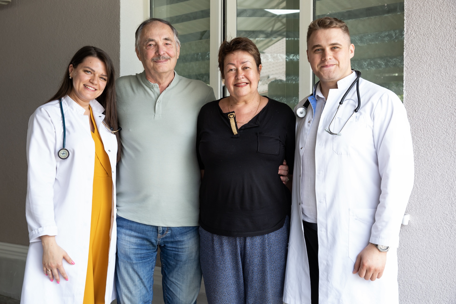 A female doctor, older man, older woman, and male doctor posing for a camera