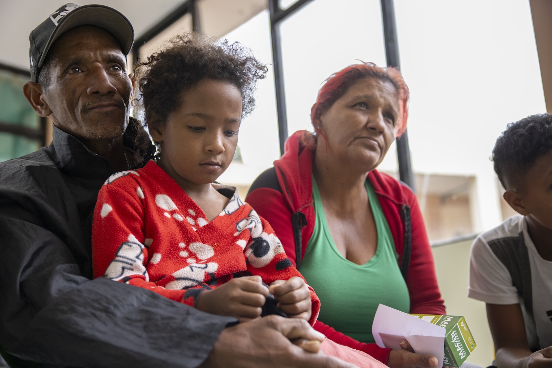 A man holding a young child sitting next to a woman and young boy.